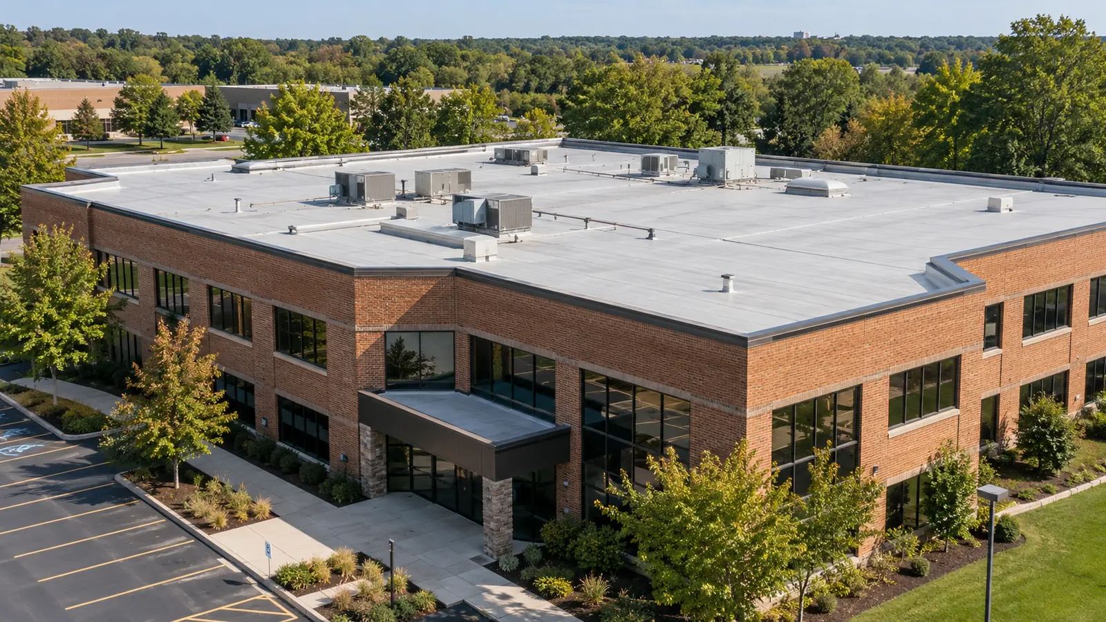Low-rise brick commercial building with a clean light-gray flat membrane roof and parking lot